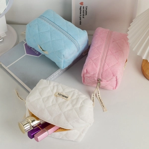 Detail of quilted plush makeup bags in blue, pink, and white with decorative ribbons