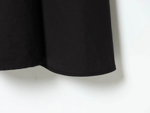 Close-up of black dress hem showing precision stitching and textured fabric detail