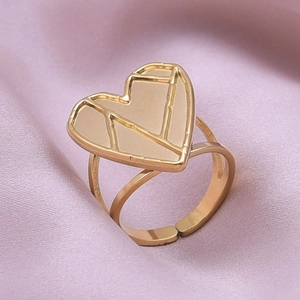 Detail of gold heart-shaped ring with geometric lines on soft purple silk