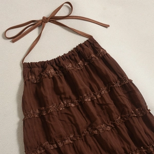 Detailed view of dark brown backless halter neck dress with layered lace and pleats