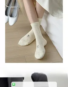 Detail of pointelle knit crew socks in cream white with a cute black bow accent