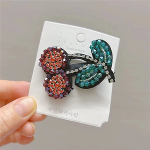 Detailed view of handmade beaded cherry hair clip with red crystals on white display card