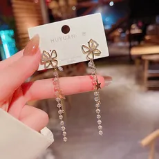 Detalle de pendientes de mariposa dorados con aguja S925 y cuentas de estrella