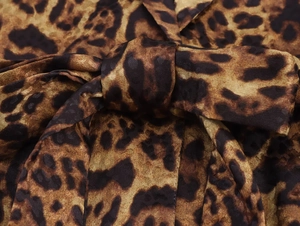 Vista detallada de la tela de satén con estampado de leopardo y un lazo decorativo
