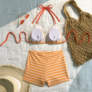Close-up of striped bikini set with halter top and high-waisted bottoms on beach accessories