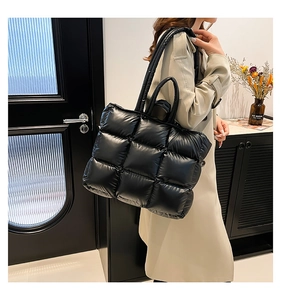 Dettaglio della borsa tote trapuntata nera con texture lucida e tracolla imbottita