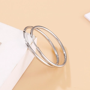 Close-up of polished silver stainless steel hoop earrings on white geometric prop