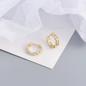 Detailed view of gold chain link hoop earrings on white card with soft fabric background