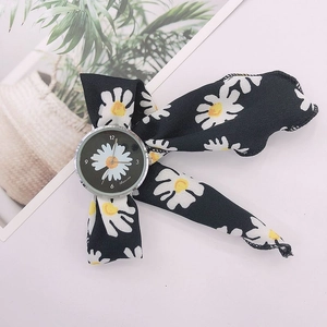 Detail of floral ribbon watch band featuring white daisies and a silver round dial