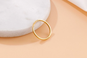 Close-up of a minimalist gold V-shaped titanium ring on white marble surface