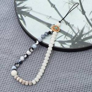 Detail of beaded phone strap featuring marble beads and turquoise wooden charm