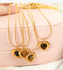 Detail of heart-shaped tiger eye and black stone pendants on gold necklaces in a jewelry box