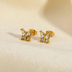Macro shot of gold butterfly stud earrings with sparkling crystals on silk fabric