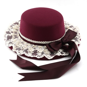 Macro detail of wine red cloche hat with ivory lace trim and large ribbon bow accent