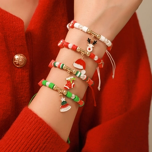 Gros plan d'un ensemble de bracelets de Noël faits main sur un fond tricoté rouge chaud