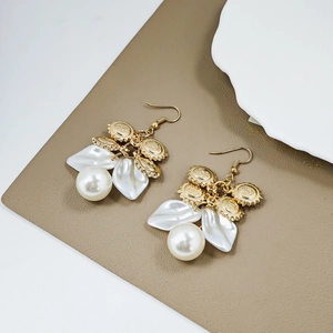 Detailed shot of gold sun charm earrings with white pearl and petal pendant drops