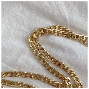 Detailed view of the shiny gold metal chain strap on a white woven background