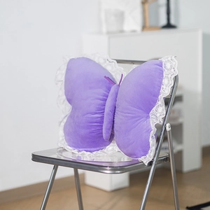 Detail of purple butterfly plush pillow with white lace trim on a modern chair