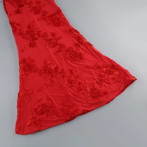 Détail d'une robe de soirée rouge avec broderie florale en 3D sur un tissu en tulle fin