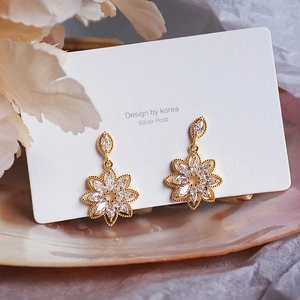 Elegant gold flower earrings with marquise zircon petals on a mother-of-pearl tray