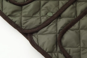 Détail de la veste matelassée vert olive avec bordure en velours côtelé marron et bouton