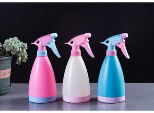 Three colorful hand-pressure spray bottles in pink, white, and blue for garden watering