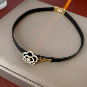 Detailed shot of leather choker with gold flower pendant and Beauty life engraving