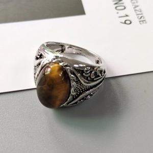 Retro mens silver alloy ring featuring a large oval yellow tiger eye stone on a grey surface