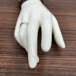 Detail view of silver ring and purple beaded bracelet on white mannequin hand