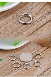 Macro detail of stainless steel jump rings next to a coin for size comparison