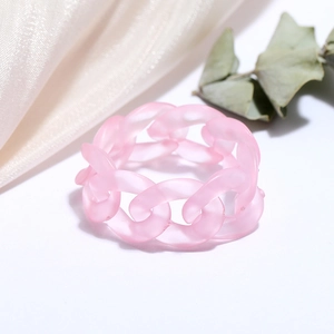 Detailed macro shot of pink matte resin cuban link ring on soft silk fabric texture