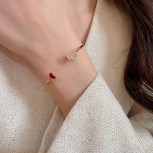 Detail of gold-plated bangle featuring a red heart and zircon butterfly on wrist