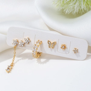 Detailed view of golden butterfly and flower earrings set with sparkling zircons