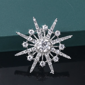 Silver starburst brooch with sparkling crystals on dark reflective surface