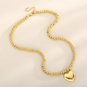 Detailed shot of golden heart pendant necklace with beaded chain and lobster clasp closure