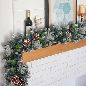 Lush snowy Christmas garland with pine cones on fireplace mantel for festive home decor