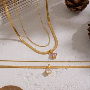 Detail of double-layer gold snake chain with pink and white zircon stone pendants