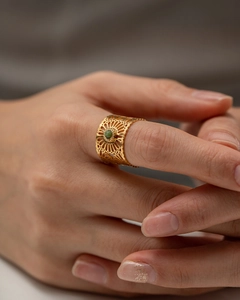 Detailed close-up of a gold hollow pattern lace ring with a green gemstone inlay