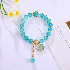 Close-up of blue crystal beaded bracelet with daisy charm and tassel detail