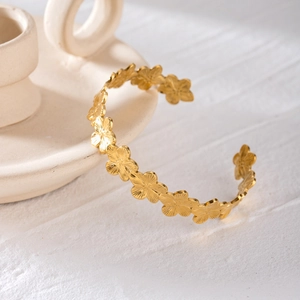 Detailed shot of golden flower-shaped stainless steel cuff on ceramic decor
