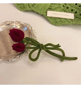 Detailed view of the dark red velvet tulip hair claw clip with green bow and stem design