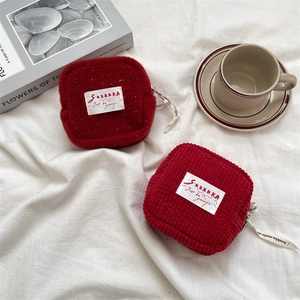 Detail of red corduroy and faux shearling mini pouches on white fabric with coffee