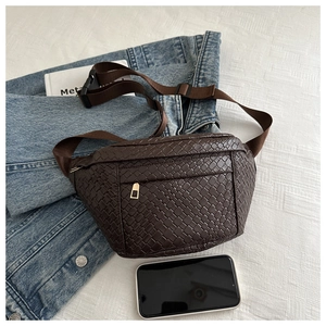 Detailed view of deep brown woven waist bag on denim jacket with phone for scale