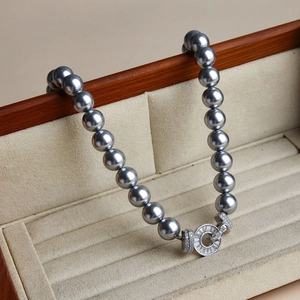 Detail of grey pearl necklace featuring a round pavé diamond clasp on velvet lining