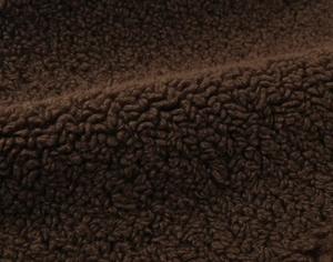 Macro shot of dark brown faux shearling fabric showing thick fleece texture and fiber detail