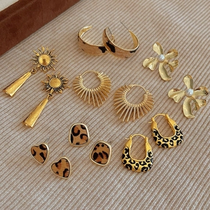 Set de boucles d'oreilles dorées avec cœurs léopard et perles sur tissu beige