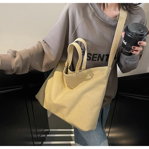 Close-up of a large beige canvas tote bag worn by a model in a lifestyle setting