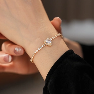 Close-up of elegant gold heart tennis bracelet with sparkling zircon stones on wrist