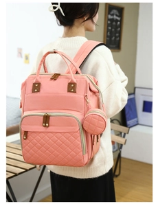 Pink multi-functional diaper backpack with quilted front pocket shown in casual setting