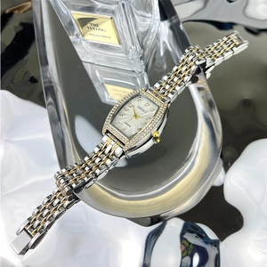 Detail view of tonneau emerald watch face with rhinestone bezel and gold silver strap